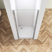 Angled view of frameless pivot shower door with polished chrome fittings